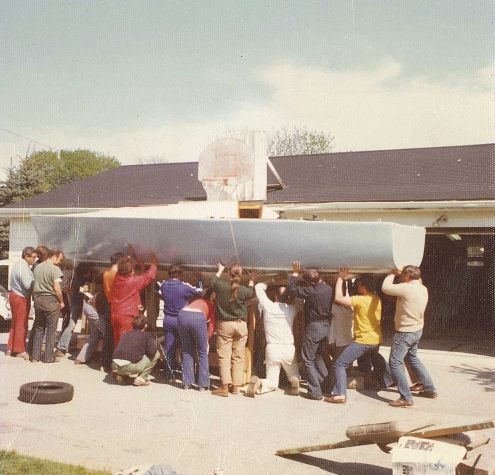Vintage photo of friends lifting J/24 hull #1 out of the Johnstone garage